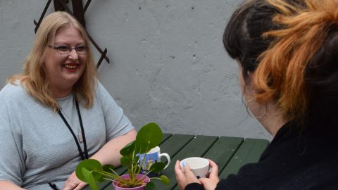 Woman smiling outside talking with someone